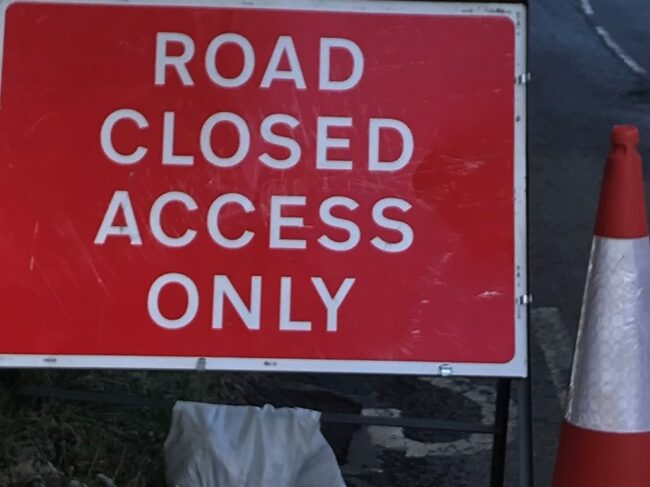 Raod Closed Access Only Sign with traffic cone landscape