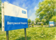 A large NHS Berrywood Hospital sign stands on grass, noting a Parish Council meeting change of venue.